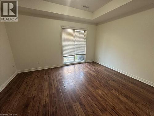Room featuring wood-finish flooring, light-colored walls, a tray ceiling, and a window with blinds - 690 Summers Common, Burlington, ON - Indoor Photo Showing Other Room