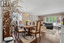 Open-concept living and dining area featuring wood-finish flooring, crown molding, and a chandelier - 