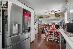 Kitchen featuring a stainless steel refrigerator with a transparent door panel, wood-finish flooring, white cabinetry, and a ceiling fan - 