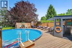 Expansive outdoor area featuring an above-ground swimming pool, a surrounding wood-finish deck, a dedicated pool house, and a wood-slat privacy fence - 