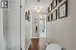 Hallway featuring wood-finish flooring, light neutral-toned walls, and a recessed ceiling light fixture - 