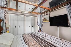 Bedroom featuring dual bi-fold closet doors, a wall-mounted television, and a decorative ceiling fixture with integrated mirrors - 