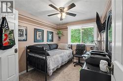 Carpeted room featuring a ceiling fan with light fixture, a window with blinds, and wall-mounted art - 