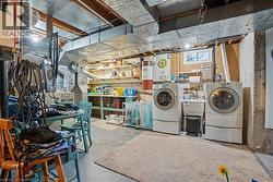 Basement utility area featuring exposed ductwork, concrete flooring, and a laundry station with a utility sink - 