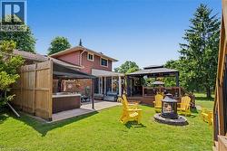 Expansive backyard featuring a central fire pit, two distinct patio areas, a wooden privacy fence, and mature perimeter trees - 