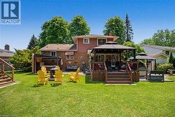 Expansive backyard featuring a multi-level deck, a covered patio area, a fire pit, and a built-in outdoor kitchen space - 