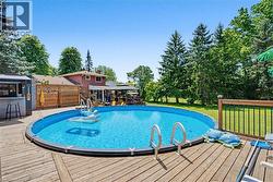 Backyard featuring an above-ground pool with surrounding wood-finish decking - 