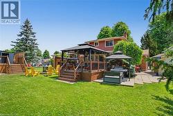 Expansive backyard featuring a manicured lawn, multi-level wooden deck, and mature trees - 