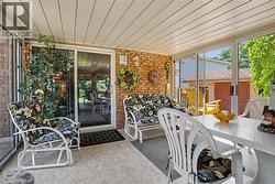 Enclosed patio featuring a brick accent wall, tile flooring, and a paneled ceiling - 