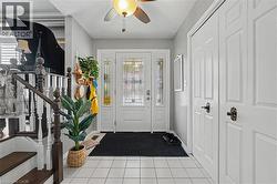 Foyer featuring white square tile flooring and a white paneled entry door with decorative glass inserts and sidelights - 