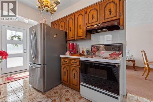 Kitchen area featuring warm wood cabinetry, a white tile backsplash, and patterned floor tiles. - 202 Ray Street N, Hamilton, ON - Indoor Photo Showing Kitchen