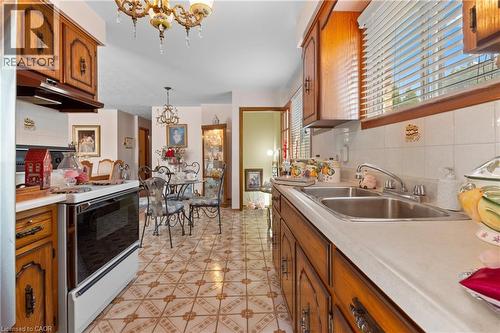 Kitchen featuring traditional wood cabinetry, a double basin stainless steel sink, and white tile backsplash. - 202 Ray Street N, Hamilton, ON - Indoor Photo Showing Kitchen With Double Sink