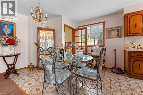 Dining area featuring patterned floor tile, a brass chandelier, and a wood-framed window with blinds. - 202 Ray Street N, Hamilton, ON - Indoor Photo Showing Dining Room