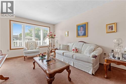 Spacious living area featuring a large window with white plantation shutters, light-toned walls, and wood trim details. - 202 Ray Street N, Hamilton, ON - Indoor Photo Showing Living Room