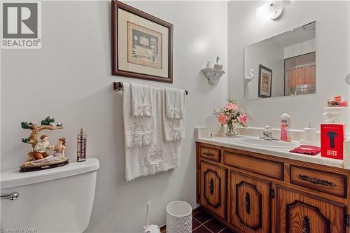 Bathroom vanity featuring a wood-finish cabinet with decorative hardware, a white countertop, and an integrated sink with a chrome faucet. - 202 Ray Street N, Hamilton, ON - Indoor Photo Showing Bathroom