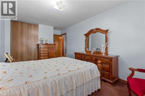 Bedroom featuring light-toned walls, wood-finish flooring, a built-in wood-finish sliding door closet, and a surface-mounted ceiling light fixture. - 202 Ray Street N, Hamilton, ON - Indoor Photo Showing Bedroom
