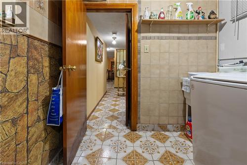 Hallway featuring patterned tile flooring, a solid wood door, and a stone-look accent wall. - 202 Ray Street N, Hamilton, ON - Indoor Photo Showing Laundry Room