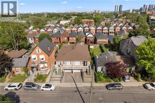 Duplex property featuring a light pink exterior with a brown shingle roof, two separate entrances with exterior staircases, and driveway. - 202 Ray Street N, Hamilton, ON - Outdoor With View
