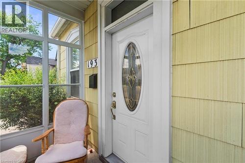 Entryway featuring a white door with decorative oval glass, brass hardware, and contrasting yellow shingle siding. - 193 Locke Street N, Hamilton, ON -  With Exterior