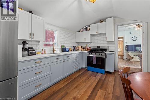 Modern kitchen featuring two-tone cabinetry, stainless steel appliances, white subway tile backsplash, light-toned countertops, and wood-finish flooring. - 193 Locke Street N, Hamilton, ON - Indoor Photo Showing Kitchen