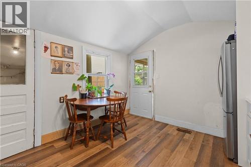 Eat in kitchen featuring wood-finish flooring, a window with natural light, a white paneled door, and a stainless steel refrigerator. - 193 Locke Street N, Hamilton, ON - Indoor Photo Showing Dining Room