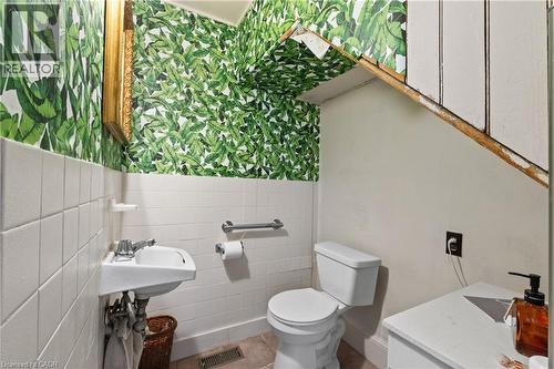 Pedestal sink with chrome faucet, white tiled wainscoting, and botanical print wallpaper. - 193 Locke Street N, Hamilton, ON - Indoor Photo Showing Bathroom