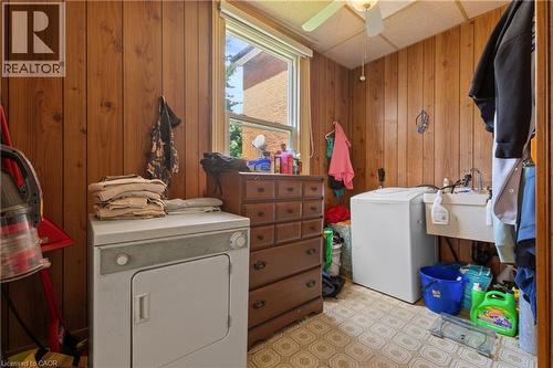 Utility room featuring wood paneling, a large window, patterned vinyl flooring, a ceiling fan, and a utility sink. - 193 Locke Street N, Hamilton, ON - Indoor Photo Showing Laundry Room