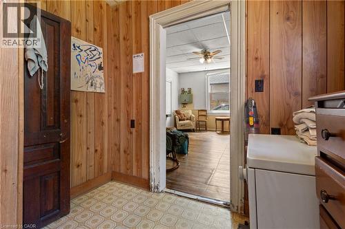 Utility room featuring wood paneling, a large window, patterned vinyl flooring, a ceiling fan, and a utility sink. - 193 Locke Street N, Hamilton, ON - Indoor