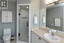 Bathroom featuring a glass-enclosed shower with subway tile, a vanity with a drop-in sink and laminate countertop, a large wall mirror, and a wall-mounted medicine cabinet - 