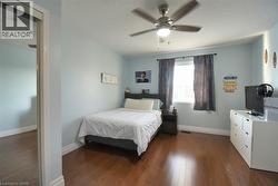 Bright room featuring wood-finish flooring, a window with blinds and dark curtains, a ceiling fan with integrated lighting, and a mirrored closet door - 