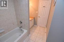 Bathroom featuring a white bathtub with chrome fixtures, tiled surround, vanity with a light-colored countertop, and a paneled door - 
