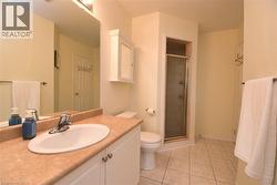 Bathroom featuring a single vanity with an integrated sink, shower enclosure with a glass door, wall-mounted medicine cabinet, and tiled flooring - 