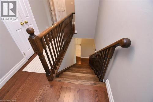 Hardwood staircase with traditional wood banister, contrasting white doors, and light gray wall paint - 188 Hunter Way, Brantford, ON - Indoor Photo Showing Other Room