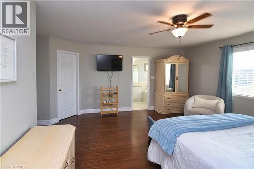 Hardwood flooring throughout, featuring a ceiling fan with integrated lighting, a wall-mounted television, and a window with horizontal blinds - 188 Hunter Way, Brantford, ON - Indoor Photo Showing Bedroom