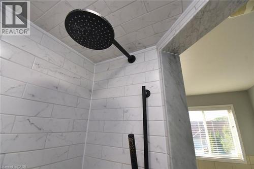 Shower enclosure featuring white subway tile with subtle grey veining, a matte black rainfall showerhead, and a matte black handheld shower - 188 Hunter Way, Brantford, ON - Indoor