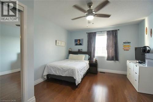 Bright room featuring wood-finish flooring, a window with blinds and dark curtains, a ceiling fan with integrated lighting, and a mirrored closet door - 188 Hunter Way, Brantford, ON - Indoor Photo Showing Bedroom