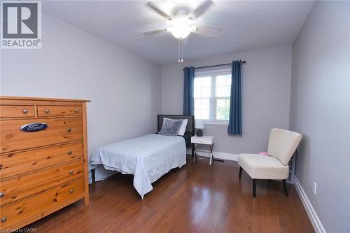 Room featuring wood-finish flooring, a double window with blinds and blue drapery, and a ceiling fan with integrated lighting - 188 Hunter Way, Brantford, ON - Indoor Photo Showing Bedroom