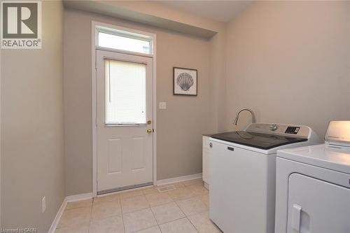 Dedicated laundry area featuring ceramic tile flooring, a white exterior door with an overhead transom window, and neutral wall tones - 188 Hunter Way, Brantford, ON - Indoor Photo Showing Laundry Room