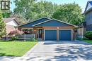 Brick and siding exterior featuring a two-car garage with blue doors, a front lawn, mature landscaping, and a porch with white railing - 25 Inverness Avenue, Hamilton, ON 