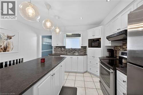 White shaker cabinetry providing extensive storage, dark countertops, and a mosaic tile backsplash - 25 Inverness Avenue, Hamilton, ON 