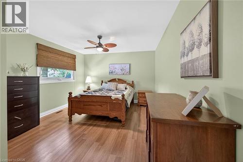 Spacious room featuring wood-finish flooring, light green walls, a window with a woven shade, and a ceiling fan with integrated lighting - 25 Inverness Avenue, Hamilton, ON 