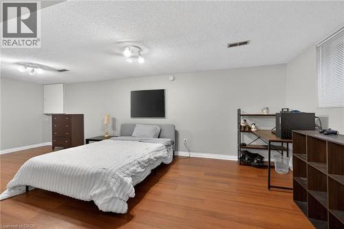 Spacious room featuring wood-finish flooring, light grey walls, and a window with blinds - 25 Inverness Avenue, Hamilton, ON 