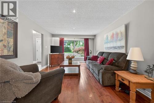Living area featuring rich wood-finish flooring, light gray wall tones, and recessed ceiling lighting - 25 Inverness Avenue, Hamilton, ON 