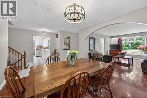 Dining area featuring wood-finish flooring, a decorative overhead light fixture, and an arched entryway to the living area - 25 Inverness Avenue, Hamilton, ON 