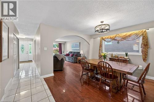 Spacious dining area featuring wood-finish flooring, an arched entryway, and a contemporary chandelier - 25 Inverness Avenue, Hamilton, ON 