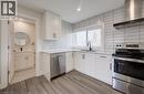 Modern kitchen featuring stainless steel appliances, white cabinetry with dark hardware, a white tile backsplash, light countertops, and wood-finish flooring - 361 Prospect Avenue, Kitchener, ON  - Indoor Photo Showing Kitchen 