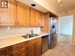 Kitchen featuring wood cabinetry, stainless steel appliances, a double basin sink, and tile flooring - 