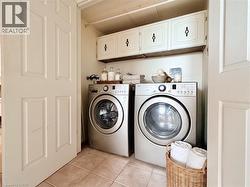 Dedicated laundry area with durable tile flooring and built-in upper cabinetry for organized storage - 