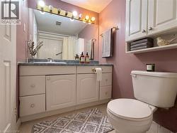 Bathroom featuring a single vanity with base cabinetry, an integrated sink, and a counter-mounted mirror with an overhead light fixture - 