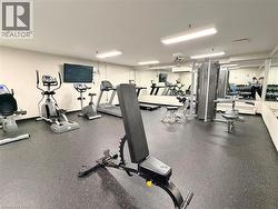 Dedicated fitness room featuring rubberized flooring, mirrored walls, and multiple exercise machines - 